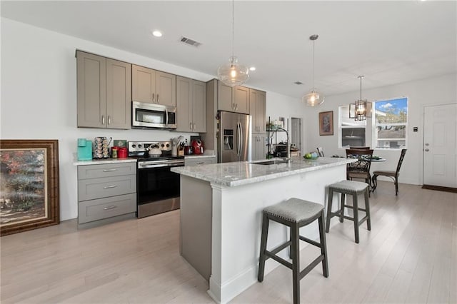 4409 Jeanne Marie Pl, New Orleans, LA 70122 - kitchen featuring gray cabinets, a sink, a kitchen bar, appliances with stainless steel finishes, and visible vents
