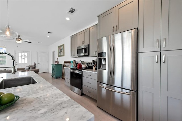 4409 Jeanne Marie Pl, New Orleans, LA 70122 - kitchen with gray cabinets, stainless steel appliances, a sink, light stone counters, and light wood-style flooring