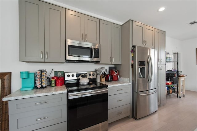 4409 Jeanne Marie Pl, New Orleans, LA 70122 - kitchen with gray cabinets, visible vents, light wood-type flooring, and stainless steel appliances