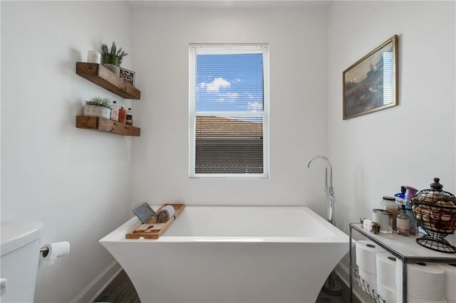 4409 Jeanne Marie Pl, New Orleans, LA 70122 - bathroom featuring a soaking tub, toilet, baseboards, and wood finished floors