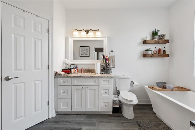 4409 Jeanne Marie Pl, New Orleans, LA 70122 - bathroom featuring vanity, toilet, baseboards, a freestanding bath, and wood finished floors