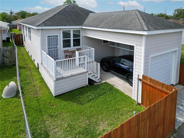 4409 Jeanne Marie Pl, New Orleans, LA 70122 - back of house with a garage, fence, a shingled roof, and a yard