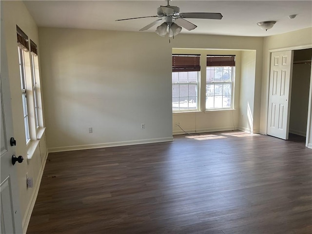 unfurnished room with baseboards, dark wood finished floors, and a ceiling fan