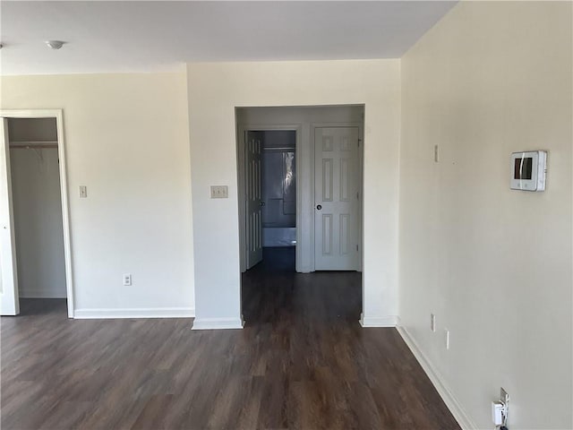 spare room featuring baseboards and dark wood-type flooring