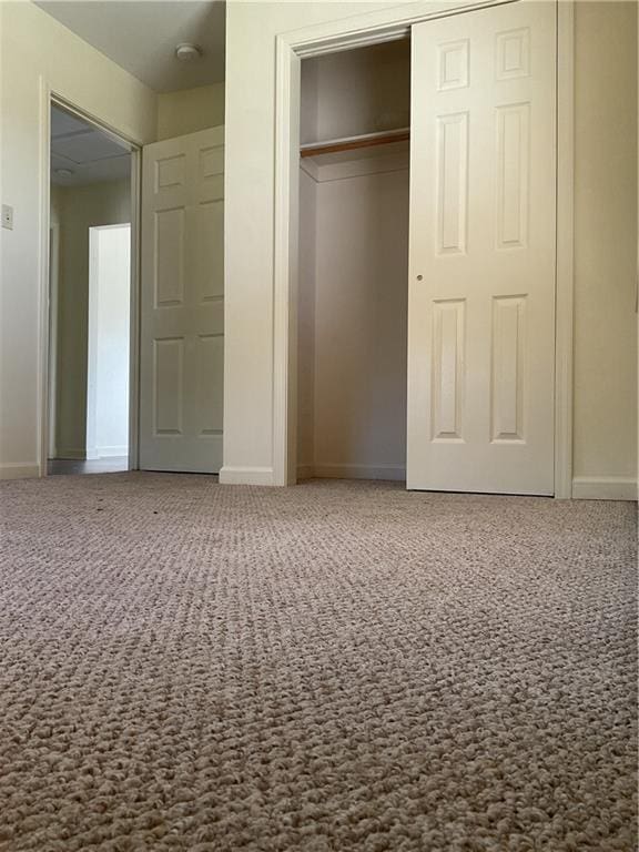 unfurnished bedroom featuring carpet, a closet, and baseboards