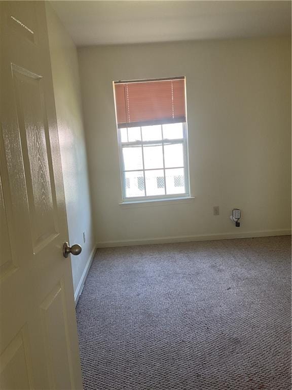 unfurnished room featuring carpet flooring and baseboards