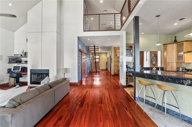 5533 Woodlawn Pl, New Orleans, LA 70124 - living room featuring a towering ceiling, dark wood-style floors, baseboards, a fireplace, and stairway
