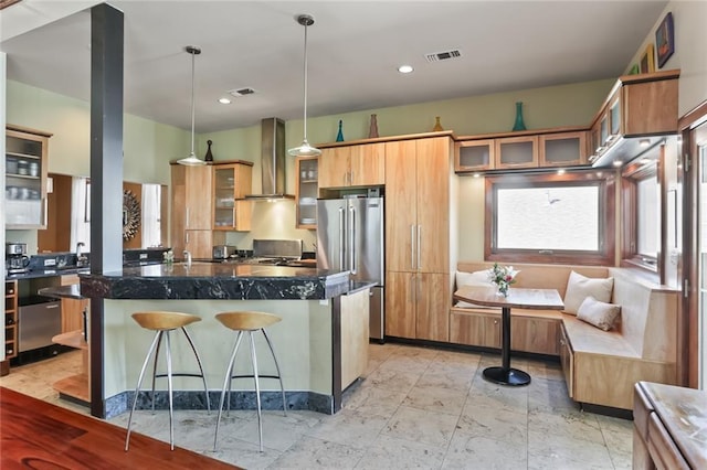 5533 Woodlawn Pl, New Orleans, LA 70124 - kitchen with wall chimney range hood, freestanding refrigerator, a center island, a kitchen breakfast bar, and glass insert cabinets