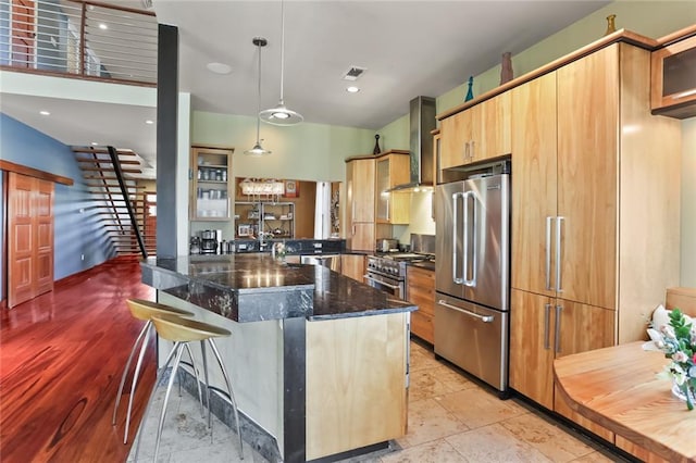 5533 Woodlawn Pl, New Orleans, LA 70124 - kitchen with high end appliances, wall chimney range hood, a kitchen breakfast bar, glass insert cabinets, and decorative light fixtures