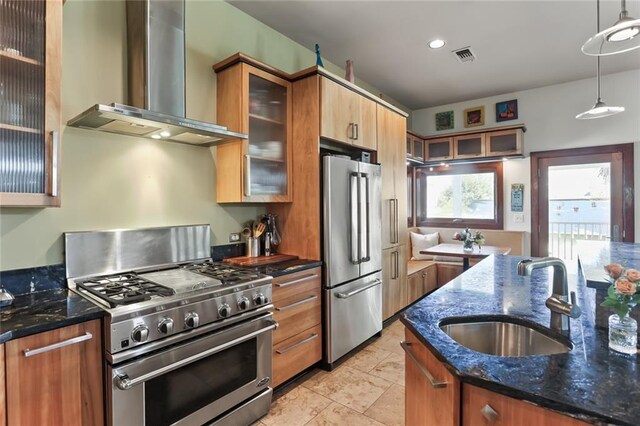 5533 Woodlawn Pl, New Orleans, LA 70124 - kitchen featuring stainless steel appliances, wall chimney exhaust hood, a sink, dark stone counters, and hanging light fixtures