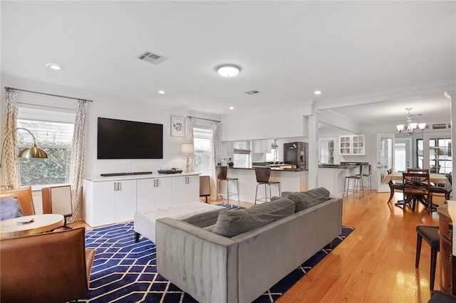 living area with visible vents, crown molding, recessed lighting, light wood-type flooring, and a notable chandelier