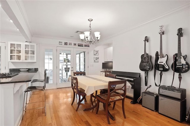 dining area with french doors, a chandelier, light wood-type flooring, visible vents, and ornamental molding