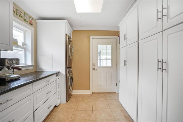 kitchen featuring white cabinets, light tile patterned flooring, dark countertops, and stacked washing maching and dryer