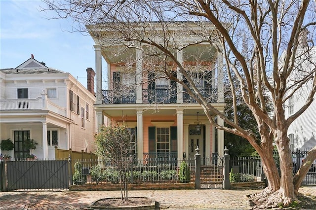 view of front of property with a balcony, a fenced front yard, and covered porch