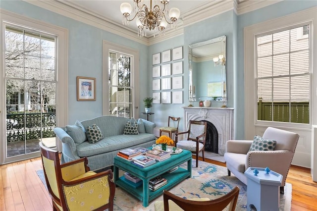 sitting room with a fireplace with flush hearth, ornamental molding, an inviting chandelier, and light wood finished floors