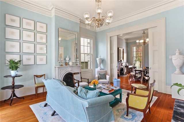 living room with baseboards, ornamental molding, wood finished floors, and a notable chandelier