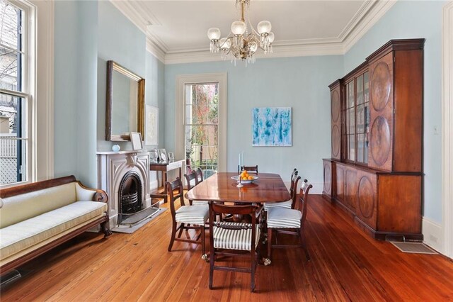 dining space with a notable chandelier, ornamental molding, and wood-type flooring