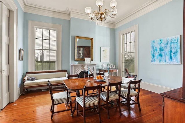 dining room featuring an inviting chandelier, hardwood / wood-style floors, crown molding, and a healthy amount of sunlight