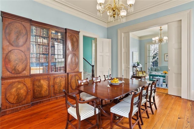 dining room with crown molding, light wood-style flooring, stairway, and a chandelier