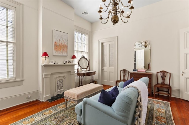 living room with a chandelier, a fireplace, wood finished floors, baseboards, and visible vents