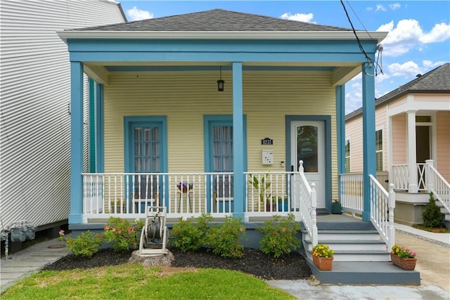 property entrance with covered porch and roof with shingles