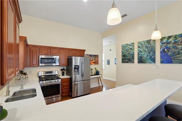 kitchen with light countertops, a sink, stainless steel appliances, and decorative light fixtures
