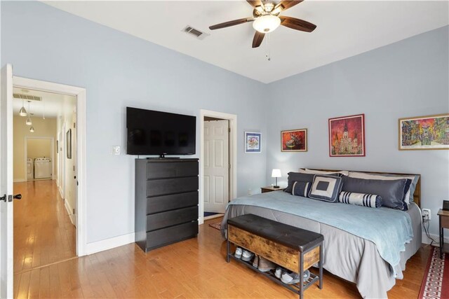 bedroom featuring baseboards, visible vents, separate washer and dryer, and wood finished floors