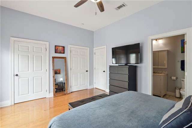 bedroom featuring baseboards, connected bathroom, ceiling fan, visible vents, and wood finished floors