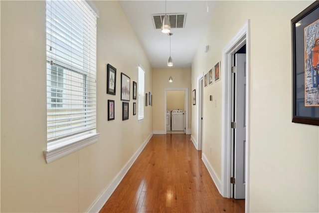 corridor with hardwood / wood-style floors, baseboards, separate washer and dryer, and visible vents
