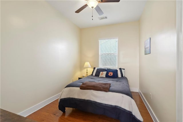 bedroom featuring baseboards, visible vents, a ceiling fan, and wood finished floors