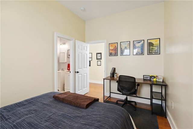 bedroom featuring baseboards, separate washer and dryer, and wood finished floors