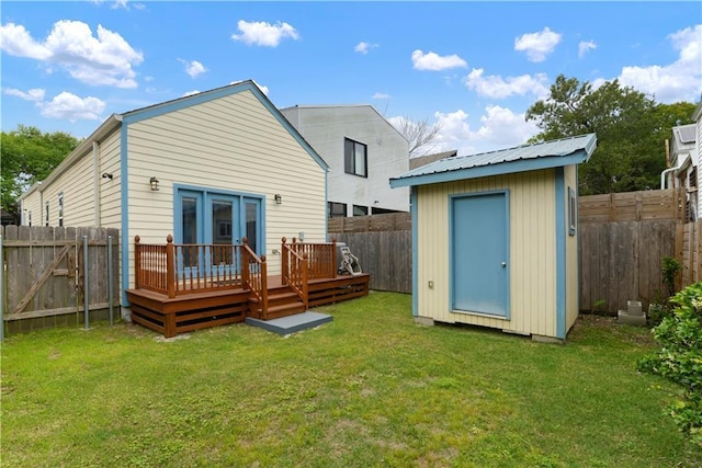 rear view of property with a shed, a wooden deck, an outdoor structure, a fenced backyard, and a yard