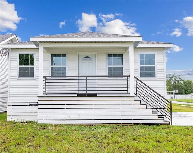 back of property featuring a porch and a lawn
