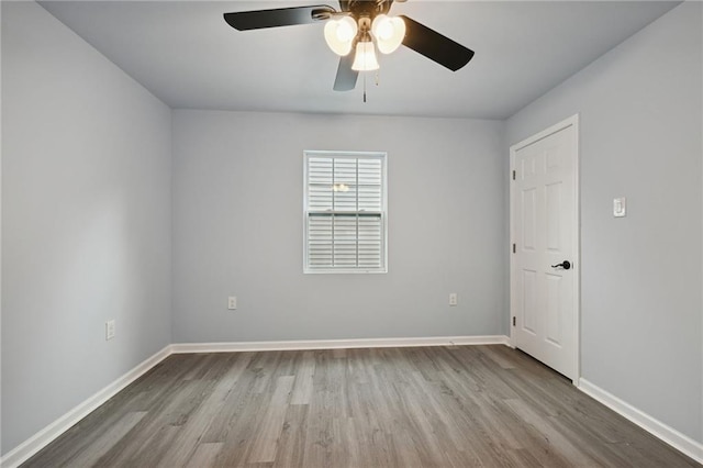 empty room featuring wood finished floors, baseboards, and ceiling fan