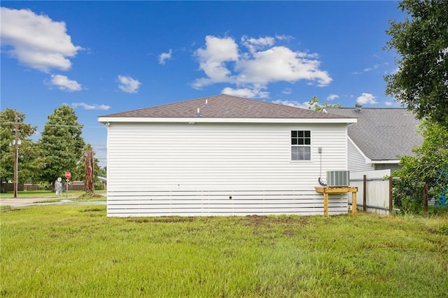 rear view of house featuring a yard, roof with shingles, and central AC