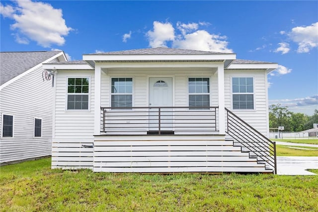 rear view of property featuring a lawn and covered porch