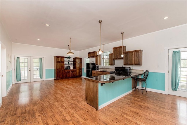 34310 Bluff Line Rd, Independence, LA 70443 - kitchen with a kitchen bar, light wood-type flooring, a wainscoted wall, a peninsula, and black appliances