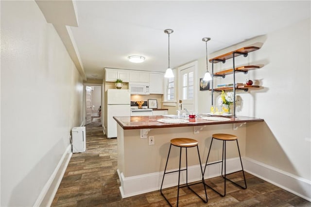 kitchen featuring white cabinetry, a kitchen breakfast bar, white appliances, hanging light fixtures, and a peninsula