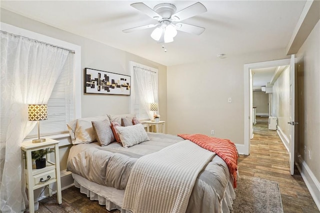 bedroom featuring baseboards, wood finished floors, and a ceiling fan