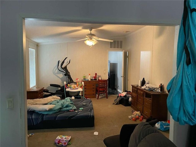 bedroom featuring a ceiling fan, visible vents, carpet floors, and crown molding