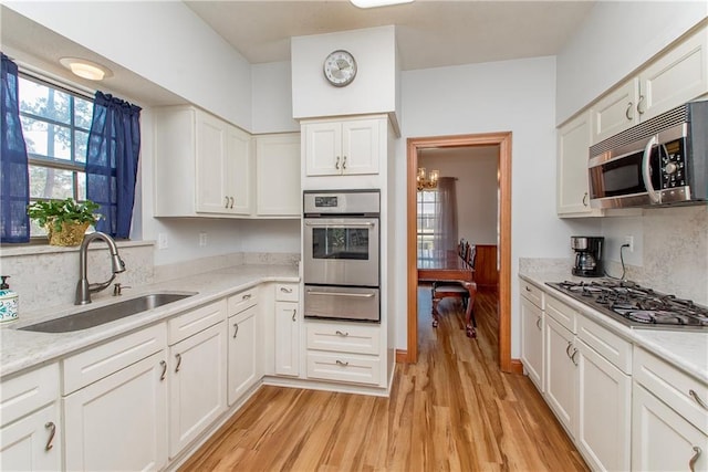 132 Country Club Dr, Covington, LA 70433 - kitchen featuring stainless steel appliances, white cabinetry, a sink, light wood-style floors, and a warming drawer