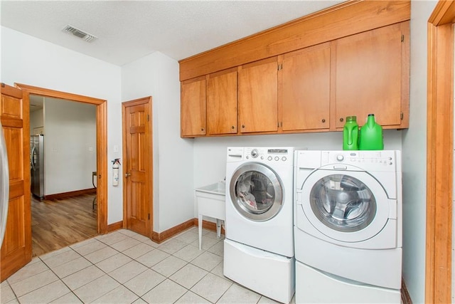132 Country Club Dr, Covington, LA 70433 - laundry room featuring light tile patterned flooring, visible vents, independent washer and dryer, baseboards, and cabinet space