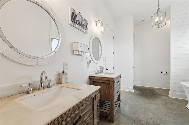 531 N Caleb Dr, Slidell, LA 70461 - bathroom featuring concrete flooring, two vanities, baseboards, a soaking tub, and a chandelier