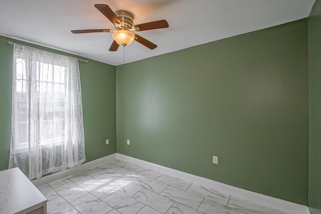 unfurnished room featuring marble finish floor, baseboards, and a ceiling fan