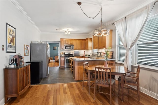 4718 Annette St, New Orleans, LA 70122 - kitchen with hardwood / wood-style flooring, a peninsula, stainless steel appliances, ornamental molding, and an inviting chandelier