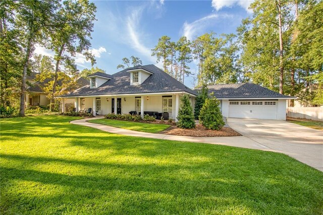 view of front facade featuring covered porch, a front yard, fence, an attached garage, and driveway