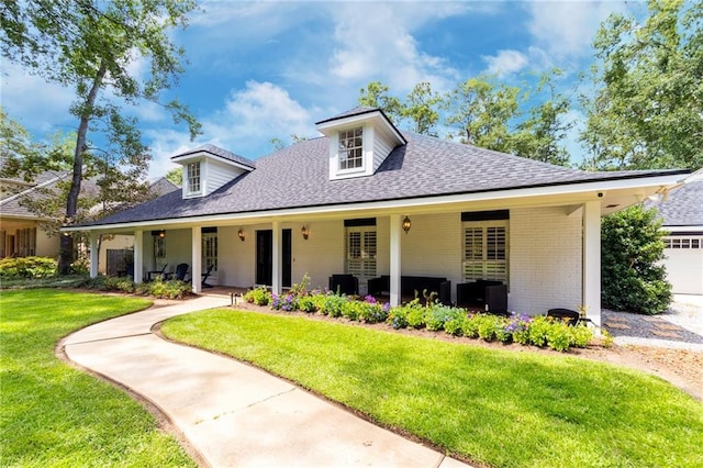 view of front of house with a shingled roof, brick siding, and a front lawn