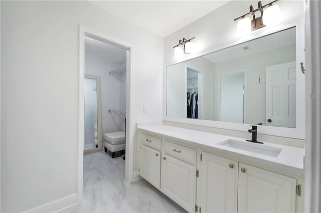 full bathroom featuring marble finish floor, baseboards, a spacious closet, and vanity