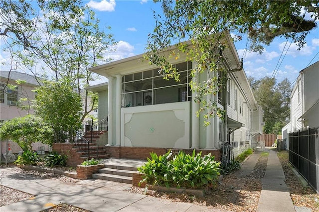 710 Burdette St, New Orleans, LA 70118 - view of front of property featuring a sunroom, fence, and stairway