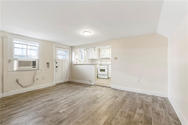 710 Burdette St, New Orleans, LA 70118 - unfurnished living room featuring cooling unit, baseboards, vaulted ceiling, and light wood-type flooring